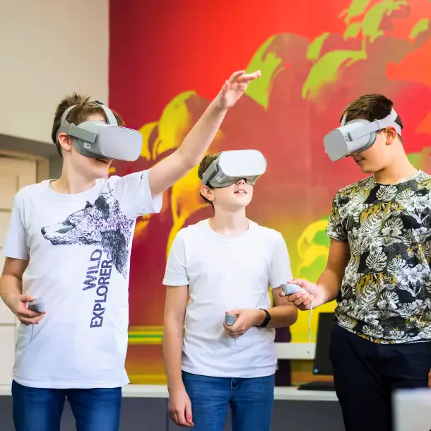Троє учнів у VR-окулярах із контролерами в руках