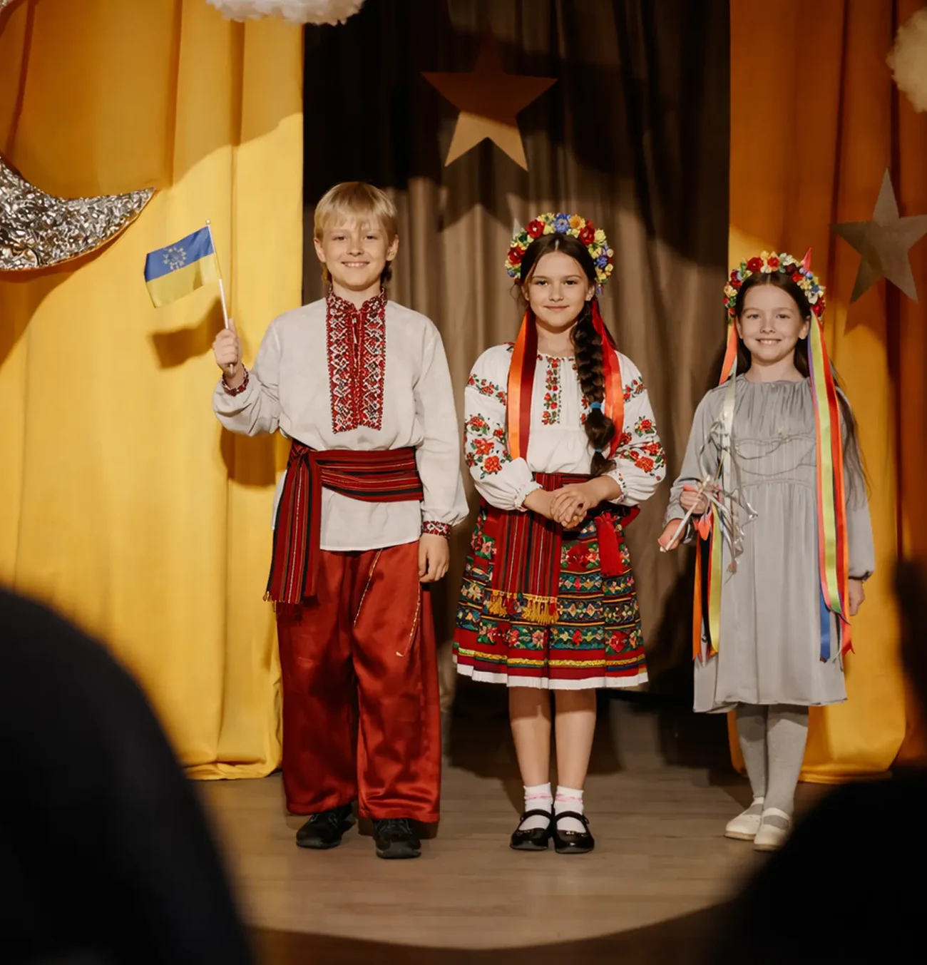 Діти у вишиванках на сцені з українським прапором